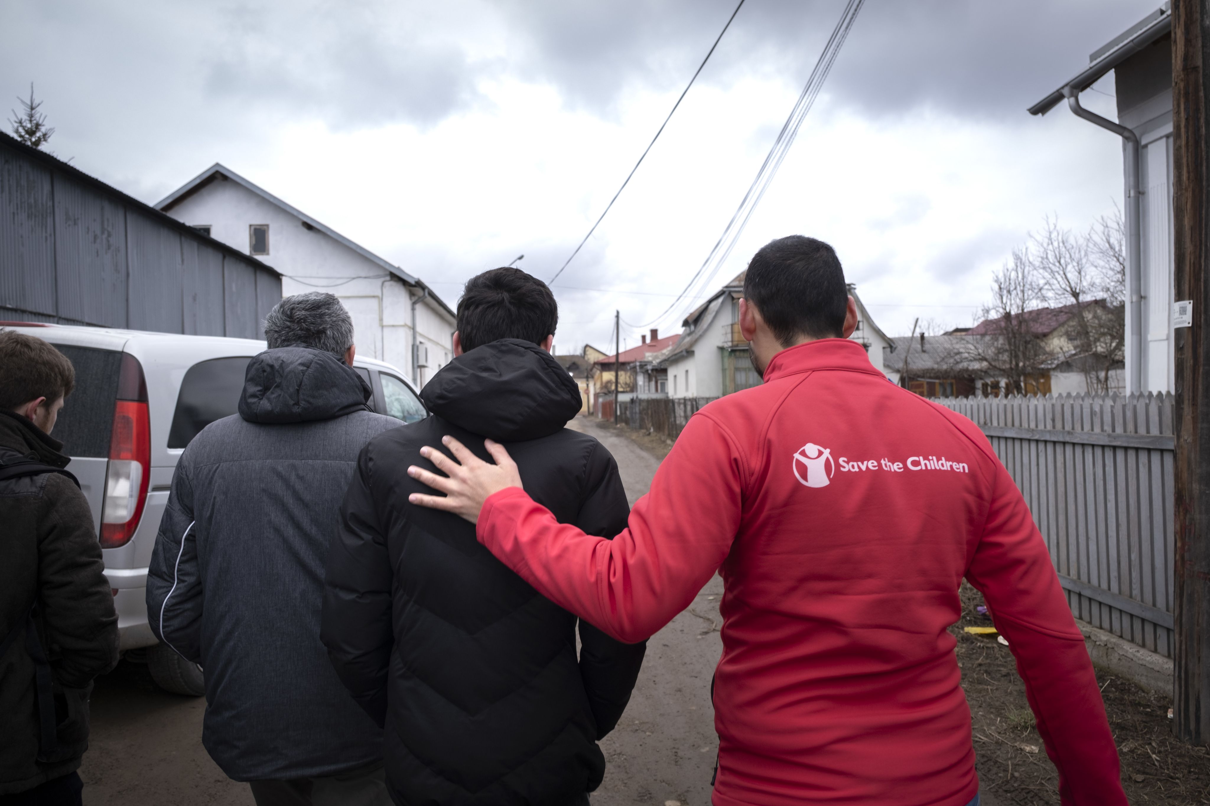 Samad walks with Save the Children staff members and his father.